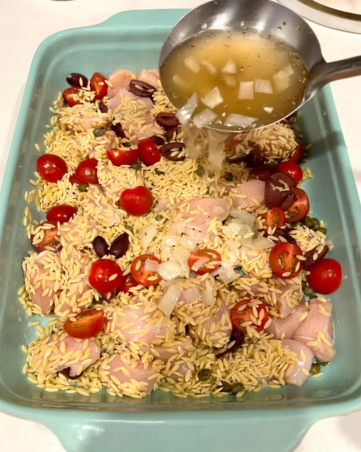 Adding hot broth mixture to the baking dish