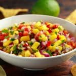 bowl of homemade pineapple salsa with tortilla cjips in background