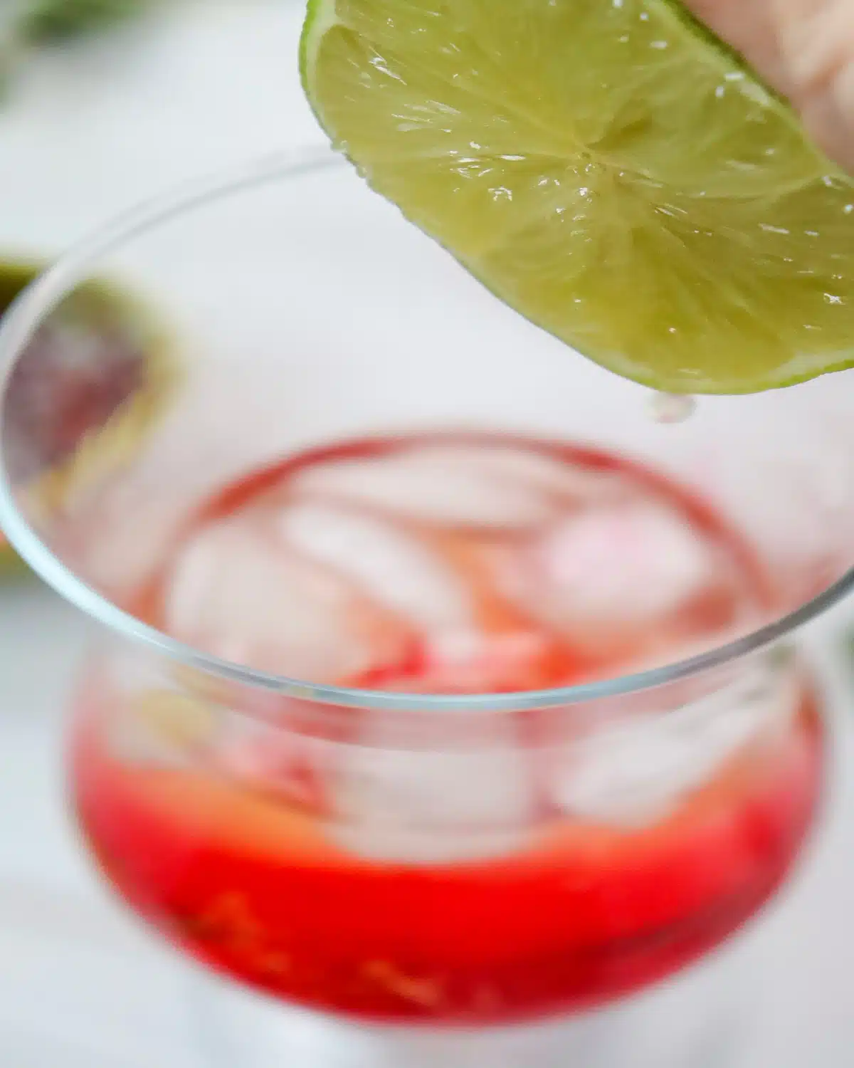 squeezing lime juice over glass of Shirley Temple drink