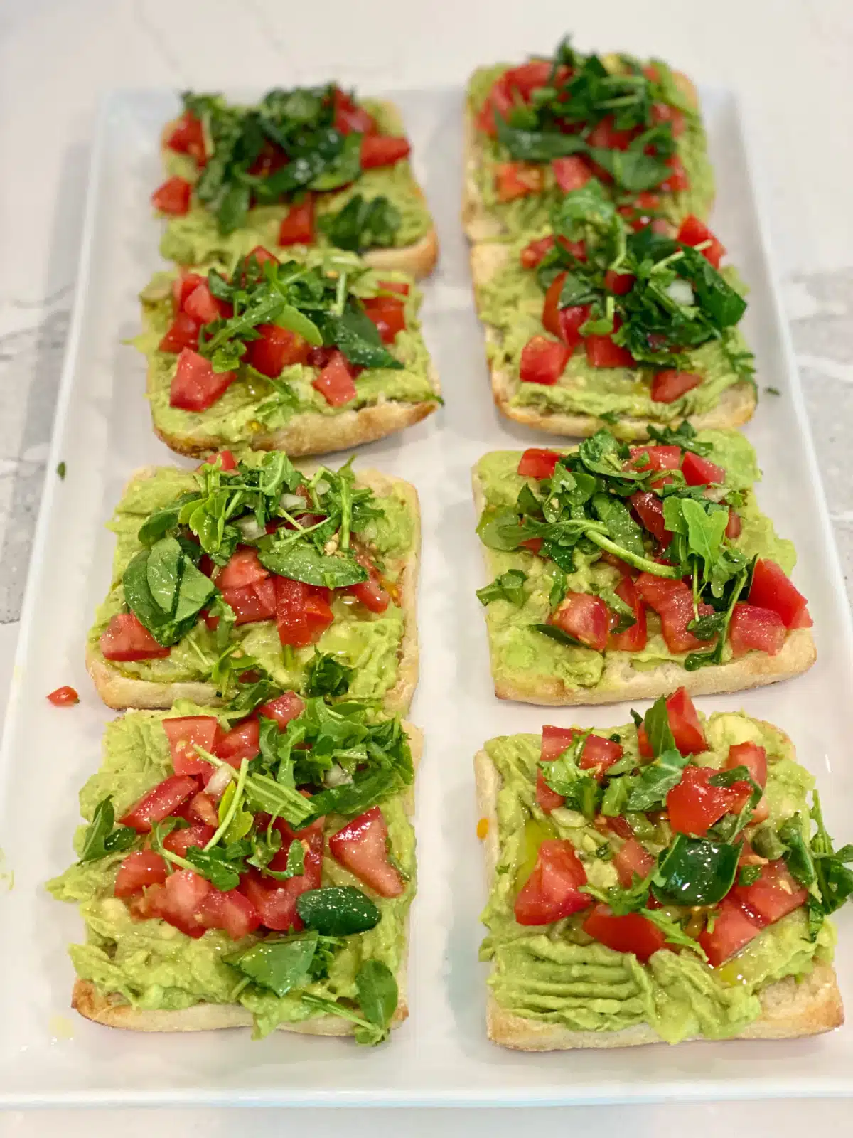 avocado toasts with tomato topping on an oblong platter