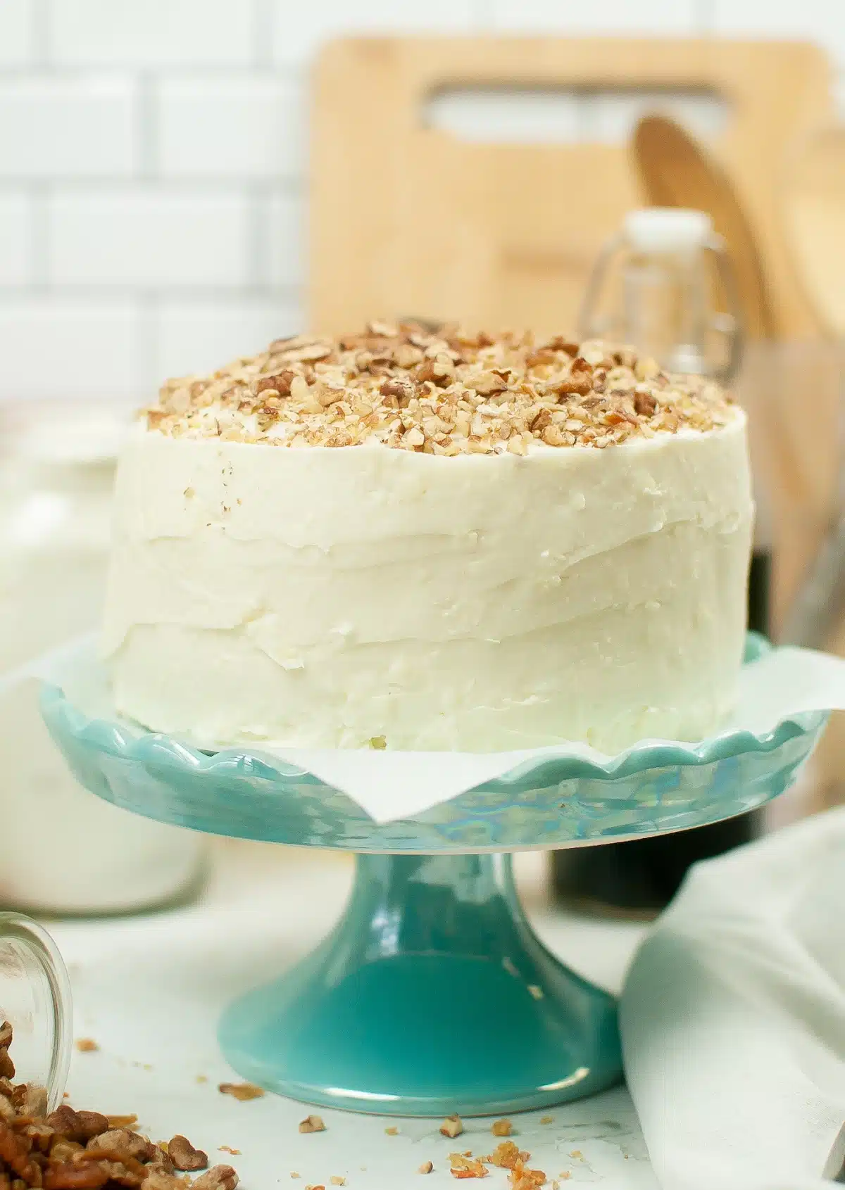 carrot cake with chopped walnuts on top on a blue cake stand
