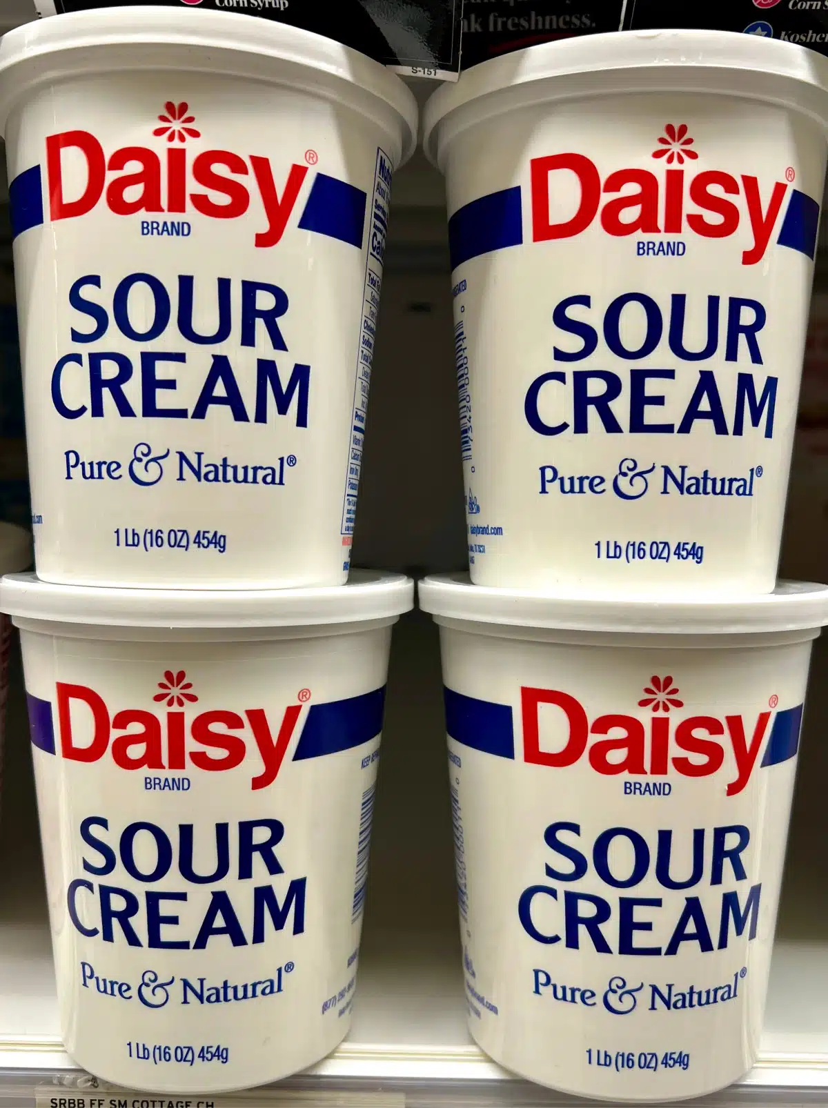 four containers of sour cream stacked up