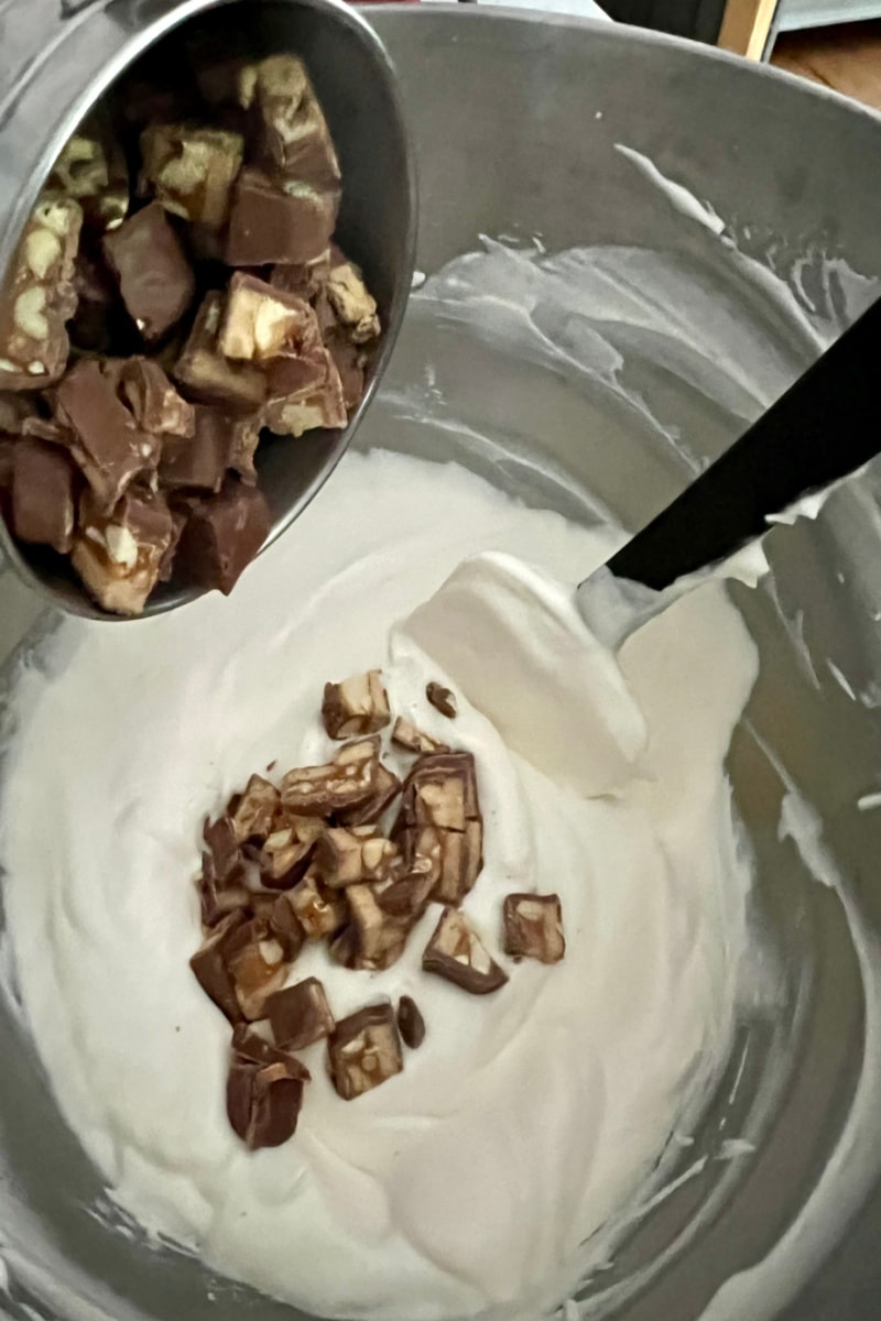 adding chopped snickers candy to ice cream