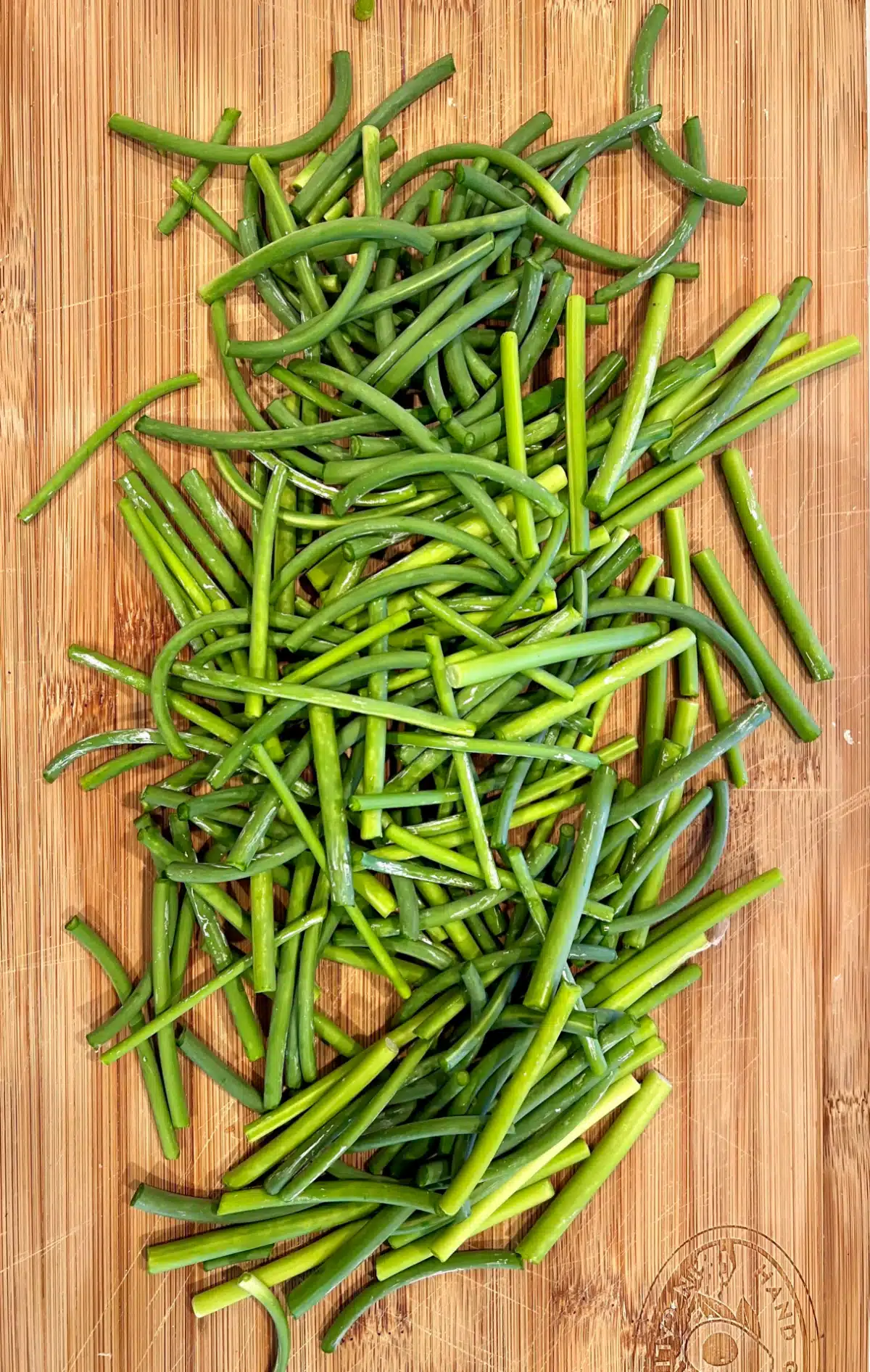 chopped garlic scapes on wooden board