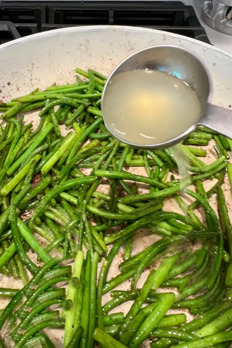 adding lemon juice to scapes in a skillet