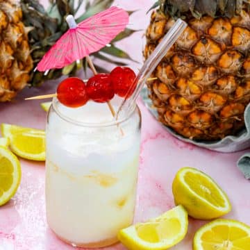 pina colada mocktail in a glass with a straw and fresh pineapples