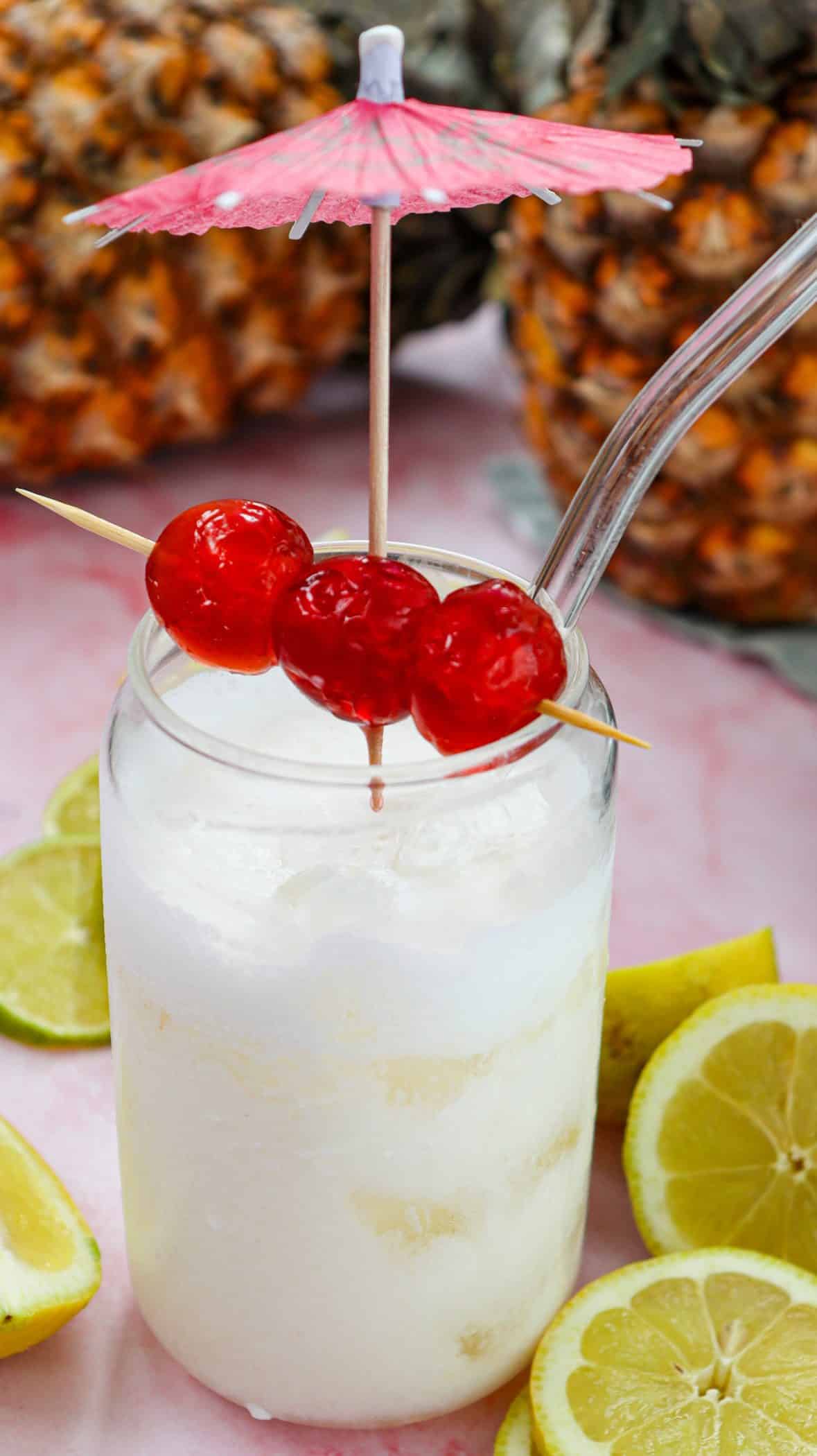 pina colada mocktail with cherries and a paper umbrella