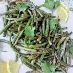 sauteed garlic scapes in serving dish with lemon slices