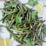 sauteed garlic scapes in serving dish with lemon slices