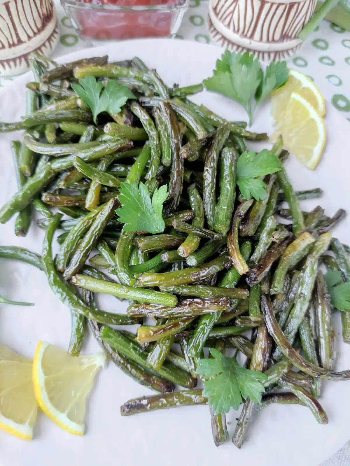 sauteed garlic scapes in serving dish with lemon slices