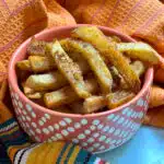 dish of seasoned french fries with a colorful napkin