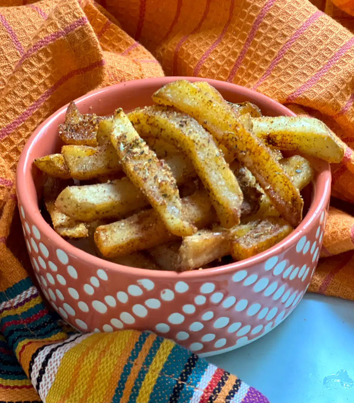 dish of seasoned french fries with a colorful napkin