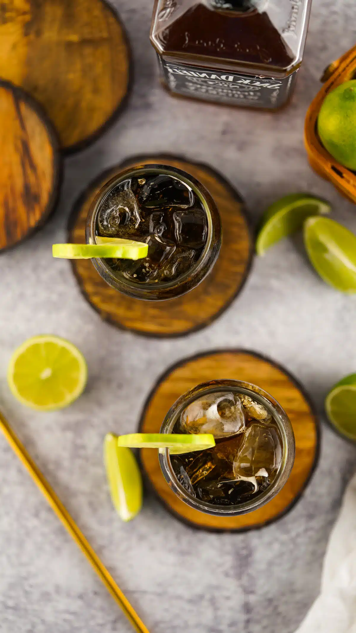 overhead of two glasses of whiskey and coke with lime slices