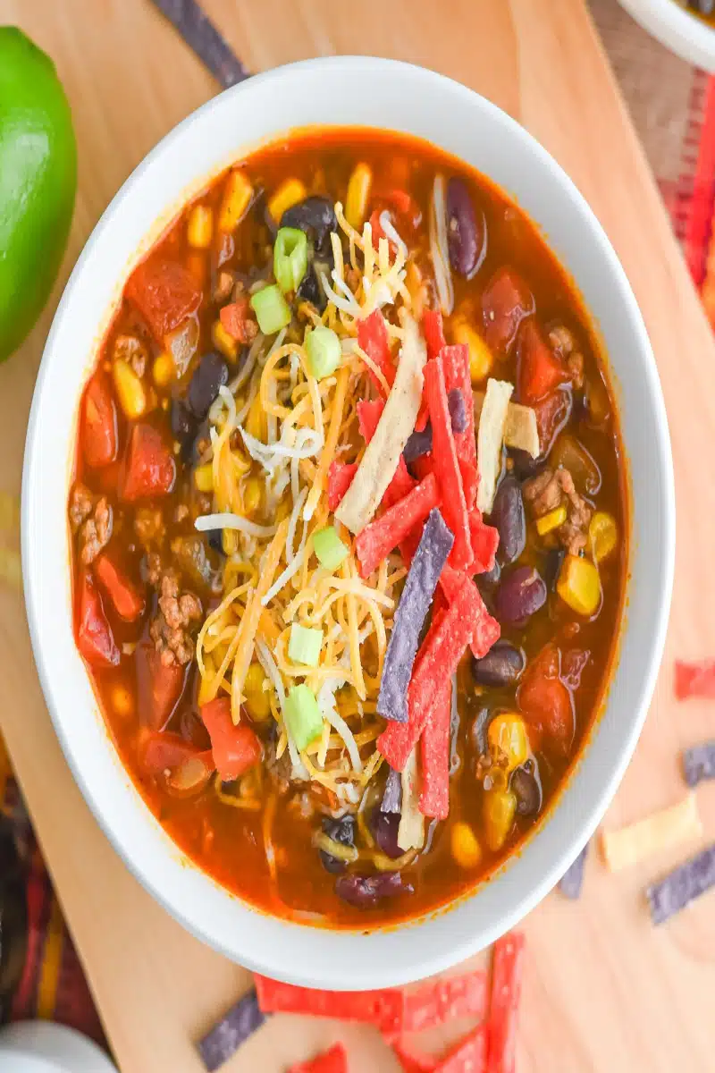 garnishing taco soup with cheese and tortilla strips