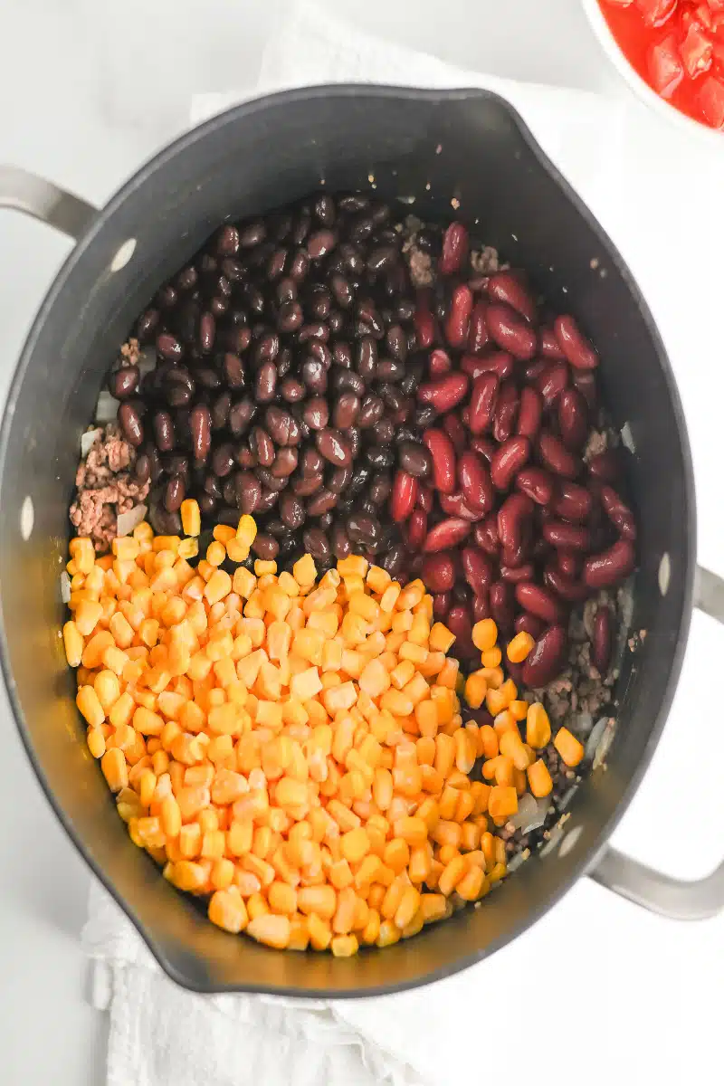 adding beans and corn to the ground beef mixture
