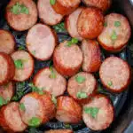 close up of sliced kielbasa with chopped parsley and text overlay
