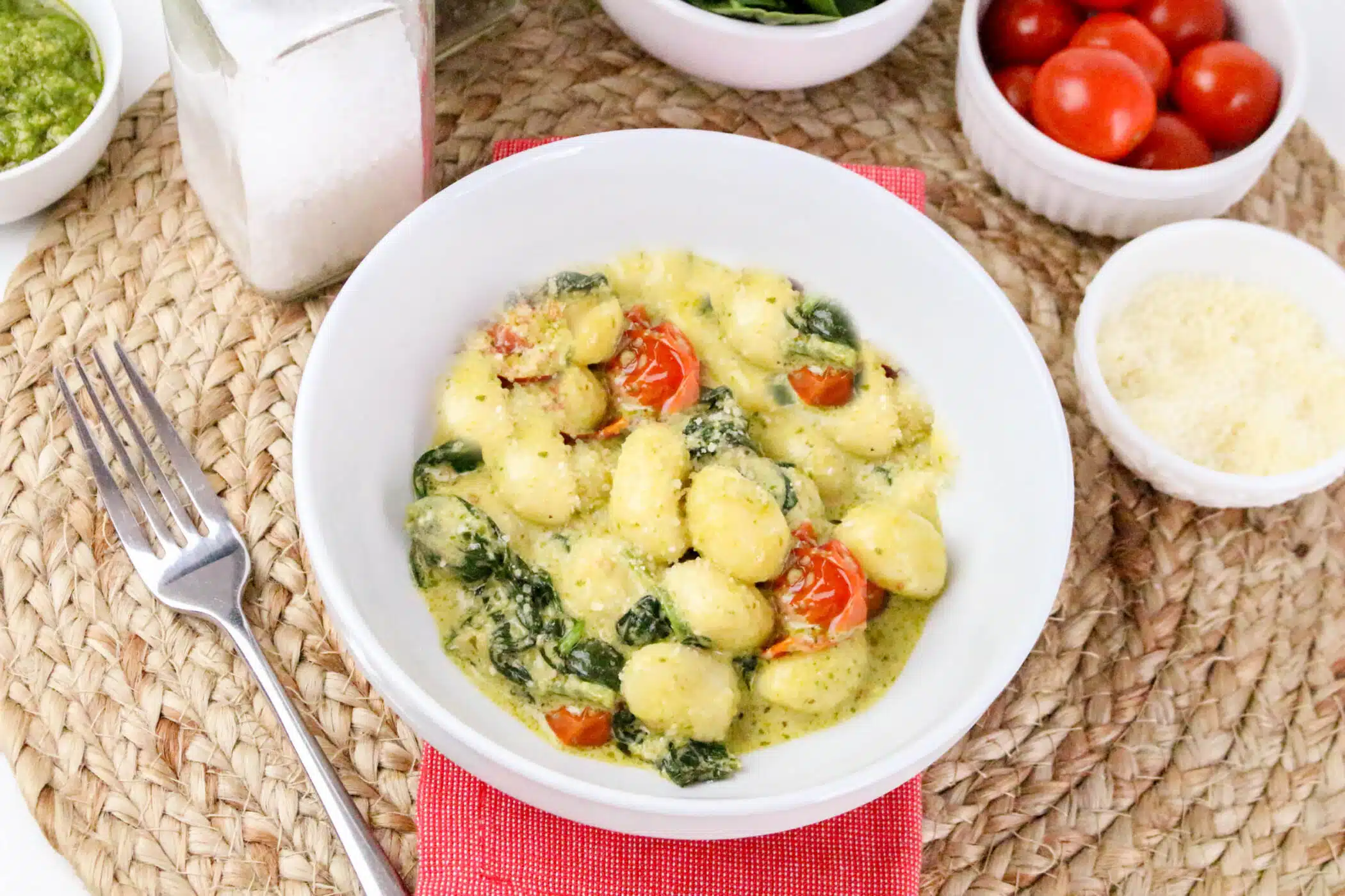 bowl of gnocchi with pesto sauce and tomatoes