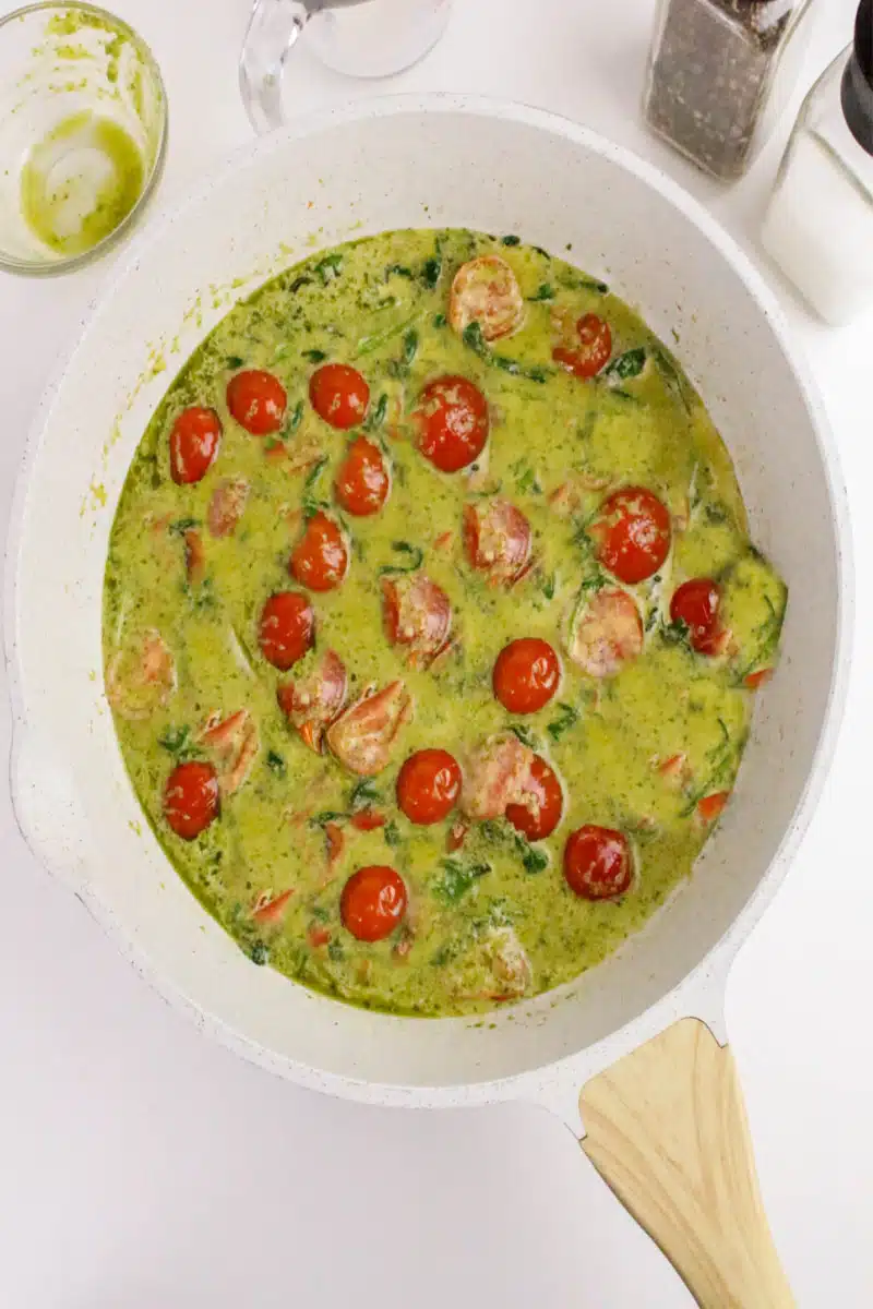adding pesto and cream to skillet with tomatoes