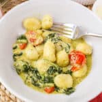 gnocchi al pesto in a white bowl with a fork