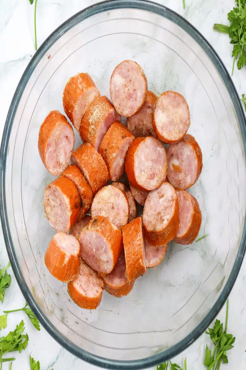 Tossing kielbasa in a bowl with seasonings