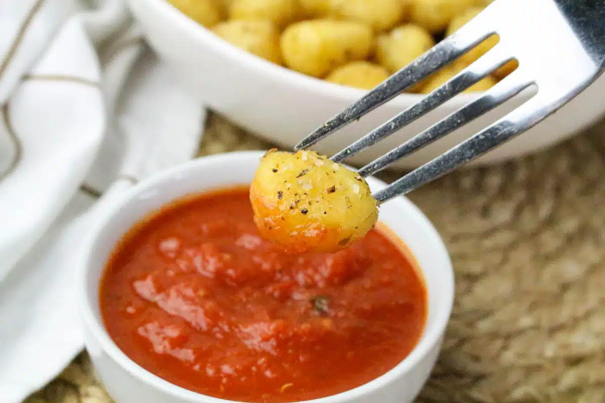 dipping gnocchi on a fork in marinara sauce