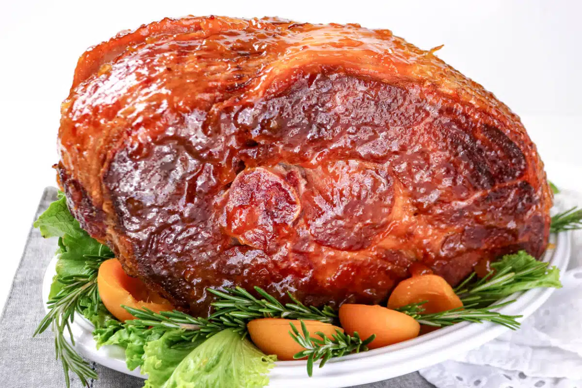 Apricot glazed spiral ham on serving platter with fresh apricots