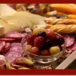 bowl of roasted grapes on a charcuterie board with text overlay