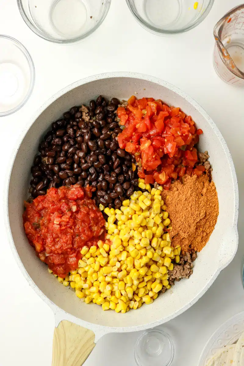 adding beans, corn, tomatoes and salsa to a skillet