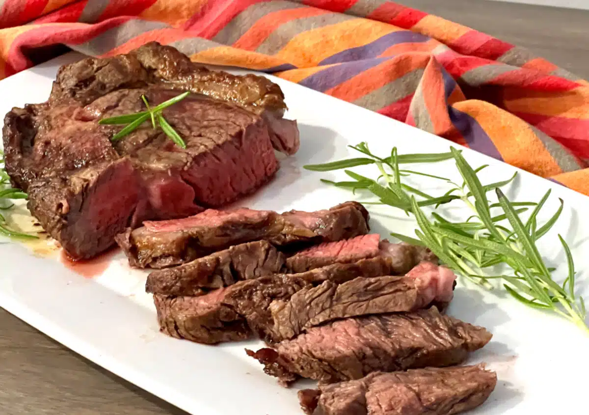 sliced ribeye steak with fresh rosemary garnish