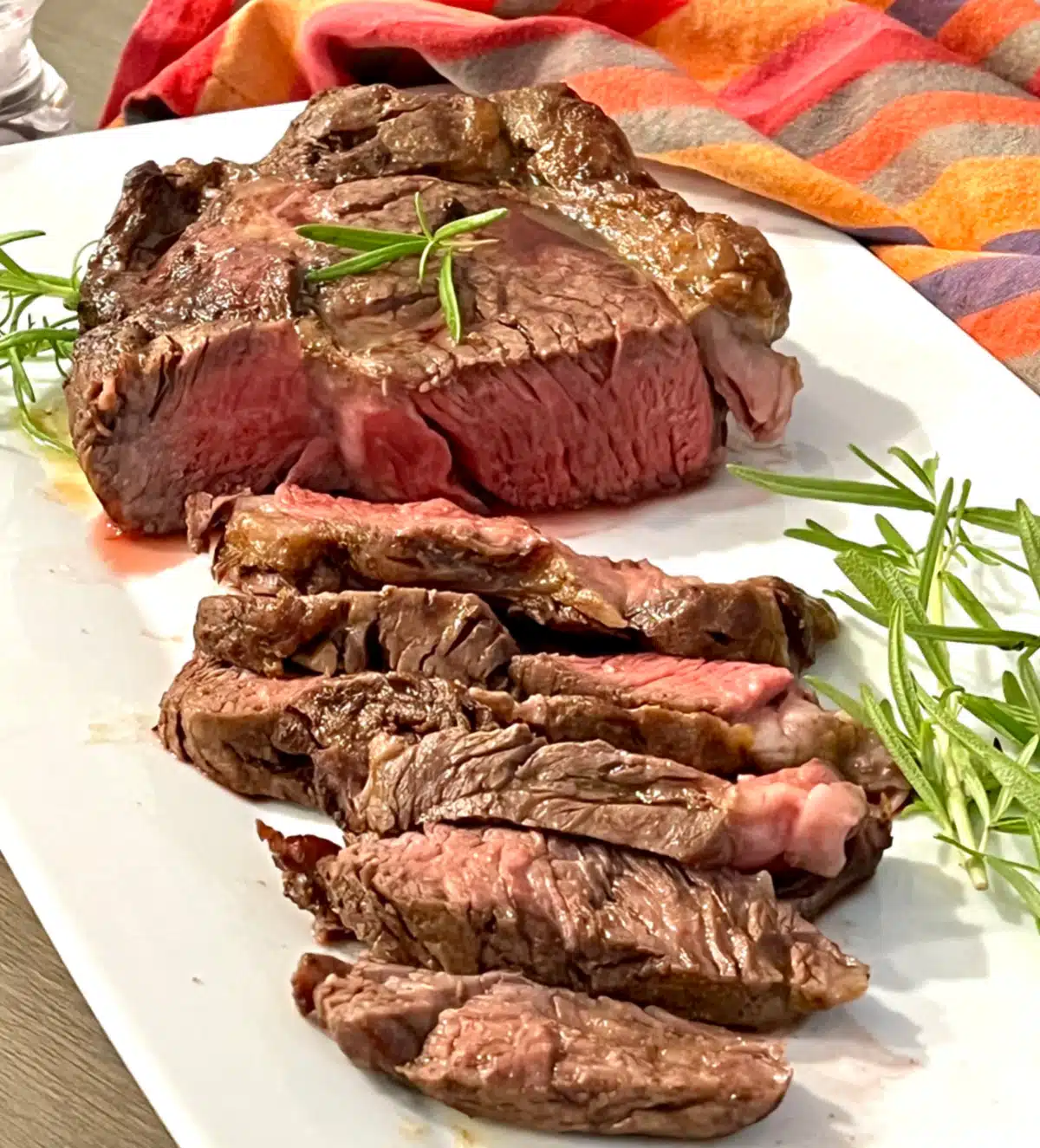 sliced rib eye steak with fresh herb garnish