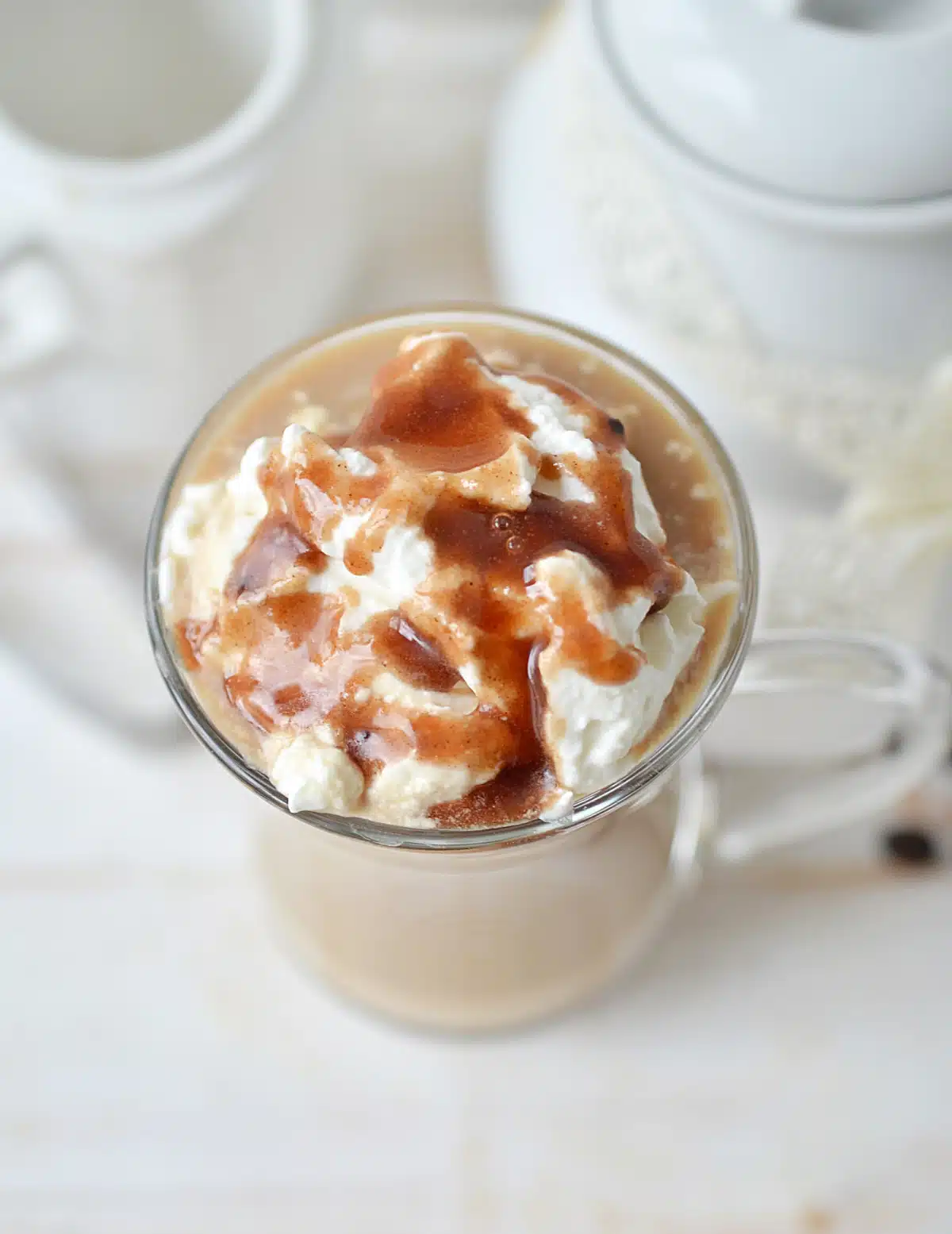 overhead photo of a mug of caramel macchiato late with whipped cream and caramel drizzle