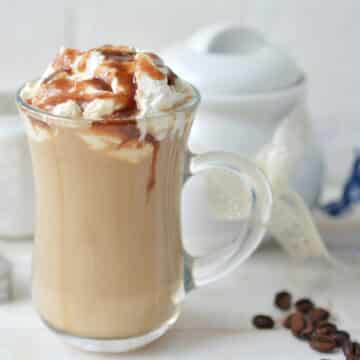 caramel macchiato latte in a glass mug with whipped cream and caramel sauce drizzle