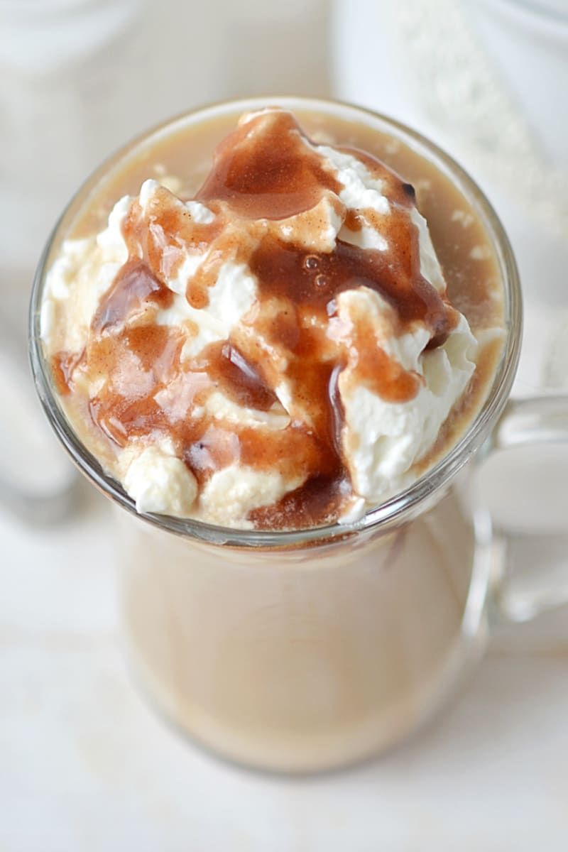 whipped cream and caramel drizzle over a latte in a mug