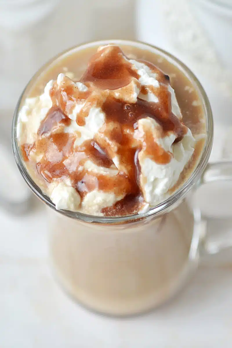 whipped cream and caramel drizzle over a latte in a mug