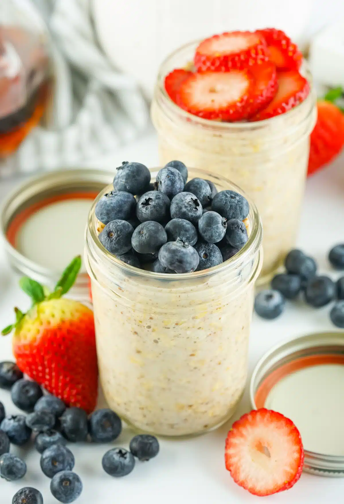 jars of overnight oatmeal topped with blueberries and strawberries
