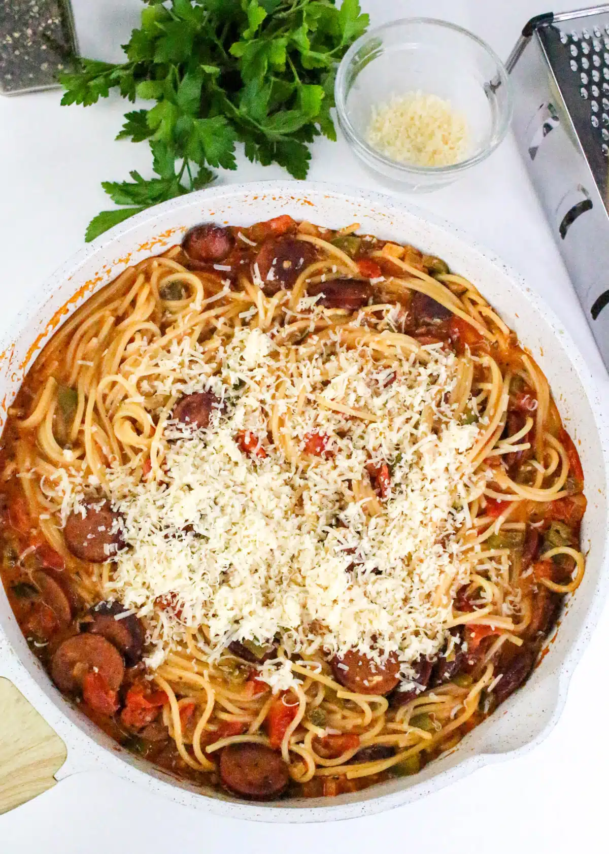 overhead of Cajun sausage and spaghetti with grated Parmesan cheese