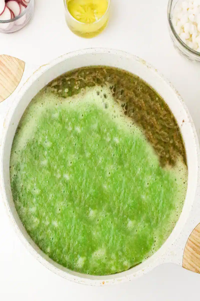 adding green sauce to the soup