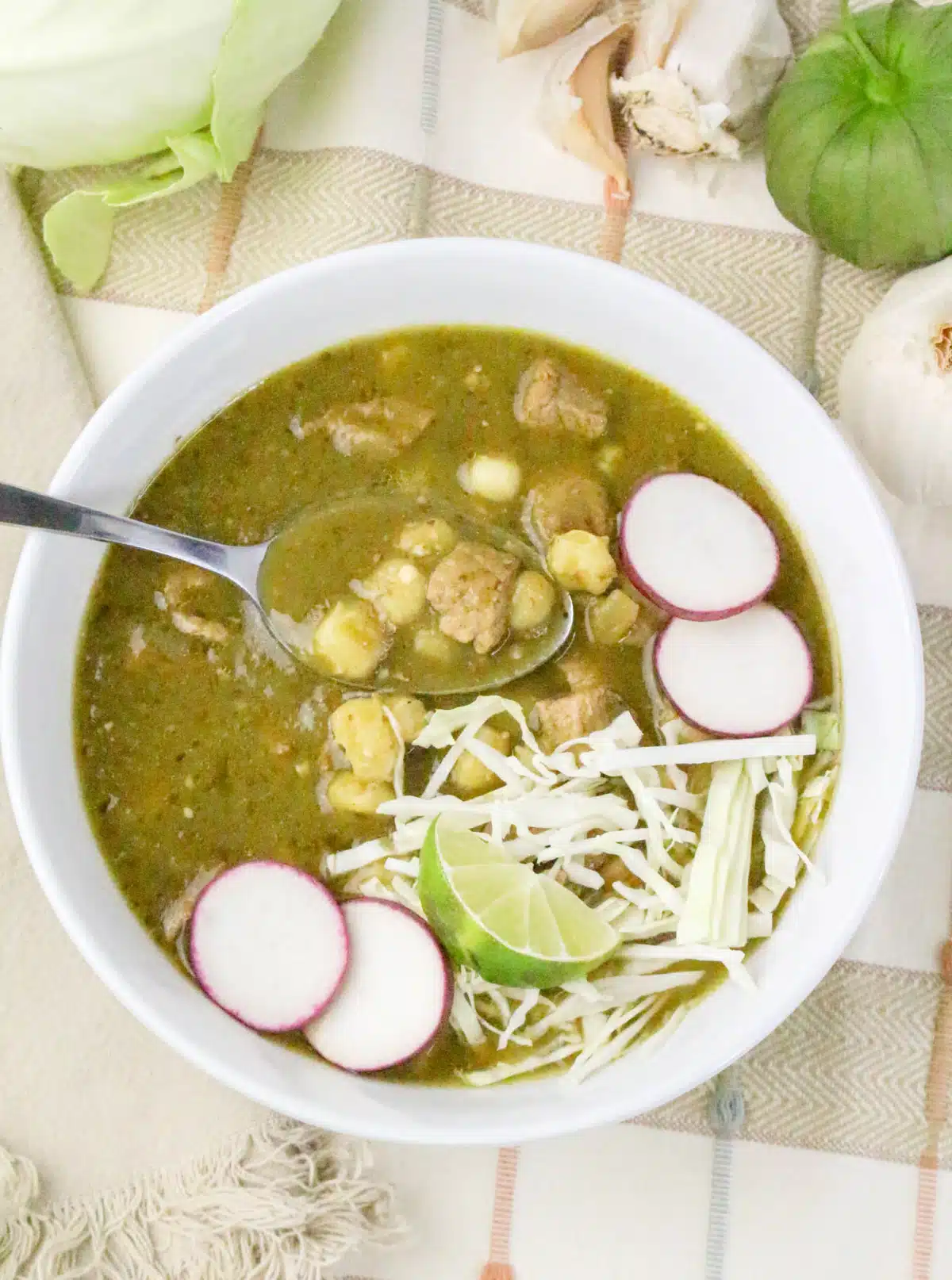 bowl of pozole soup with toppings and a spoon