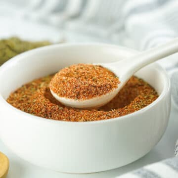 Cajun seasoning in a white bowl with a spoon