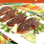 platter of blackened chicken with lime and parsley and text overlay