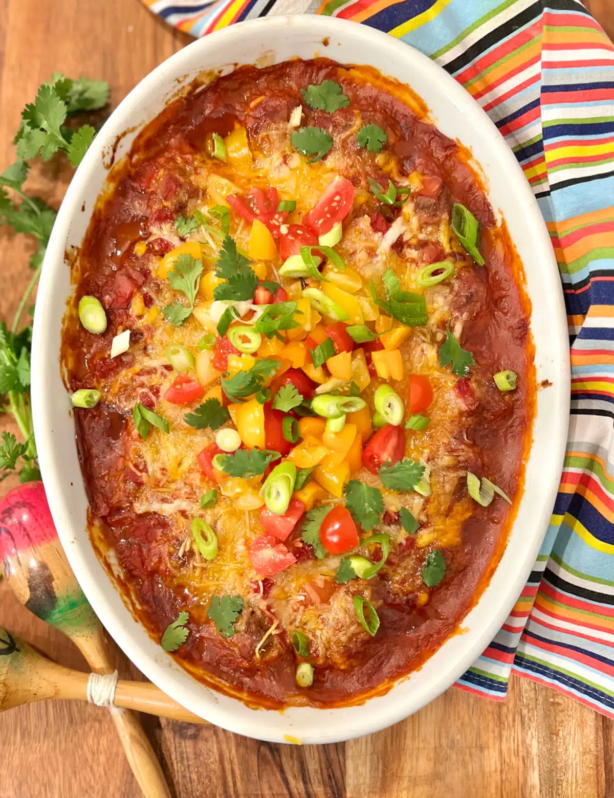 overhead of a taco casserole in an oval baking dish with colorful napkin
