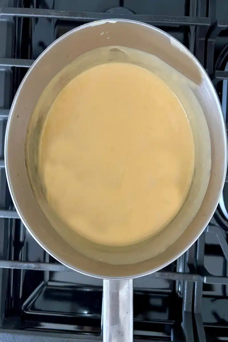 making cheese sauce for mac and cheese in a pot
