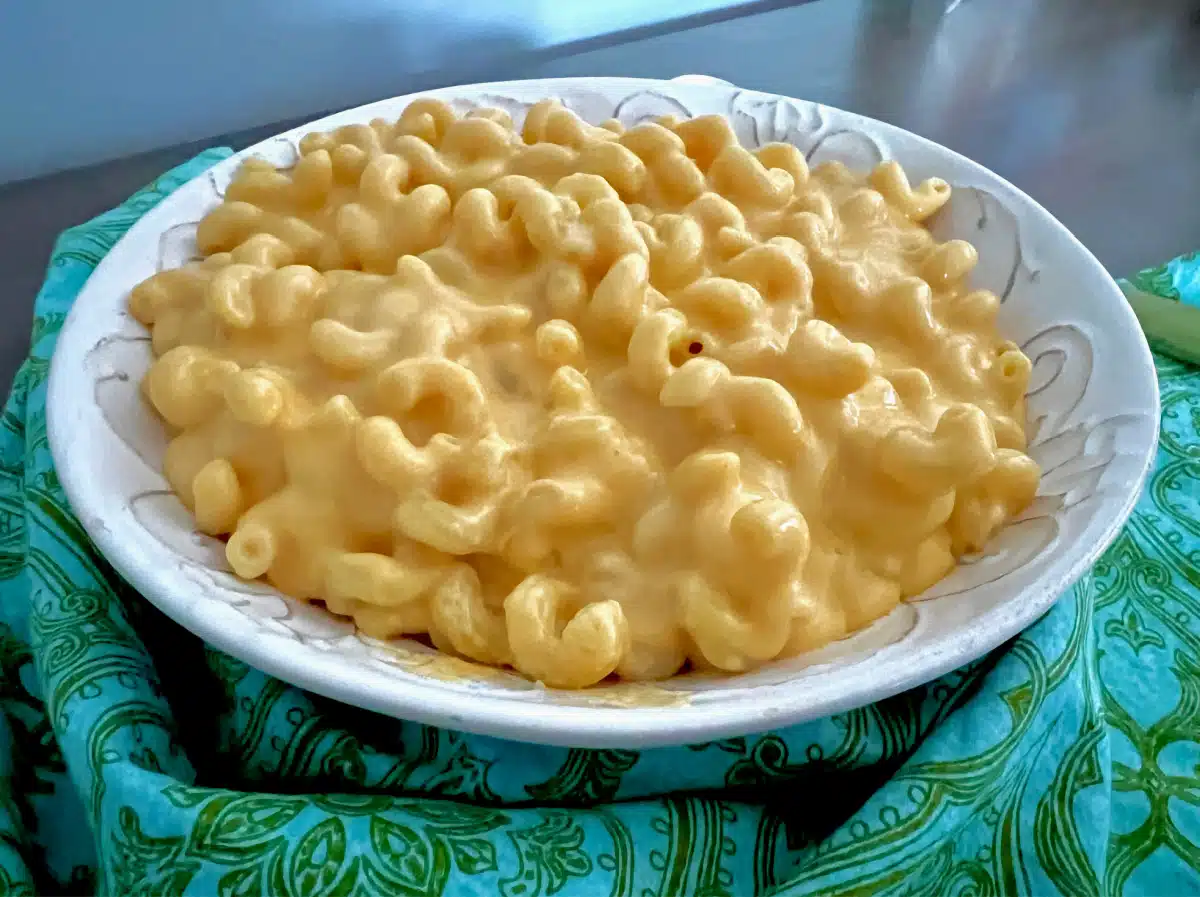 Velveeta mac and cheese in a white serving bowl with blue napkin