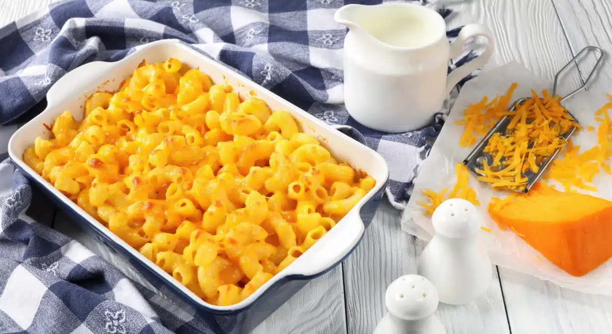 macaroni and cheese in baking dish with shredded cheese an grater