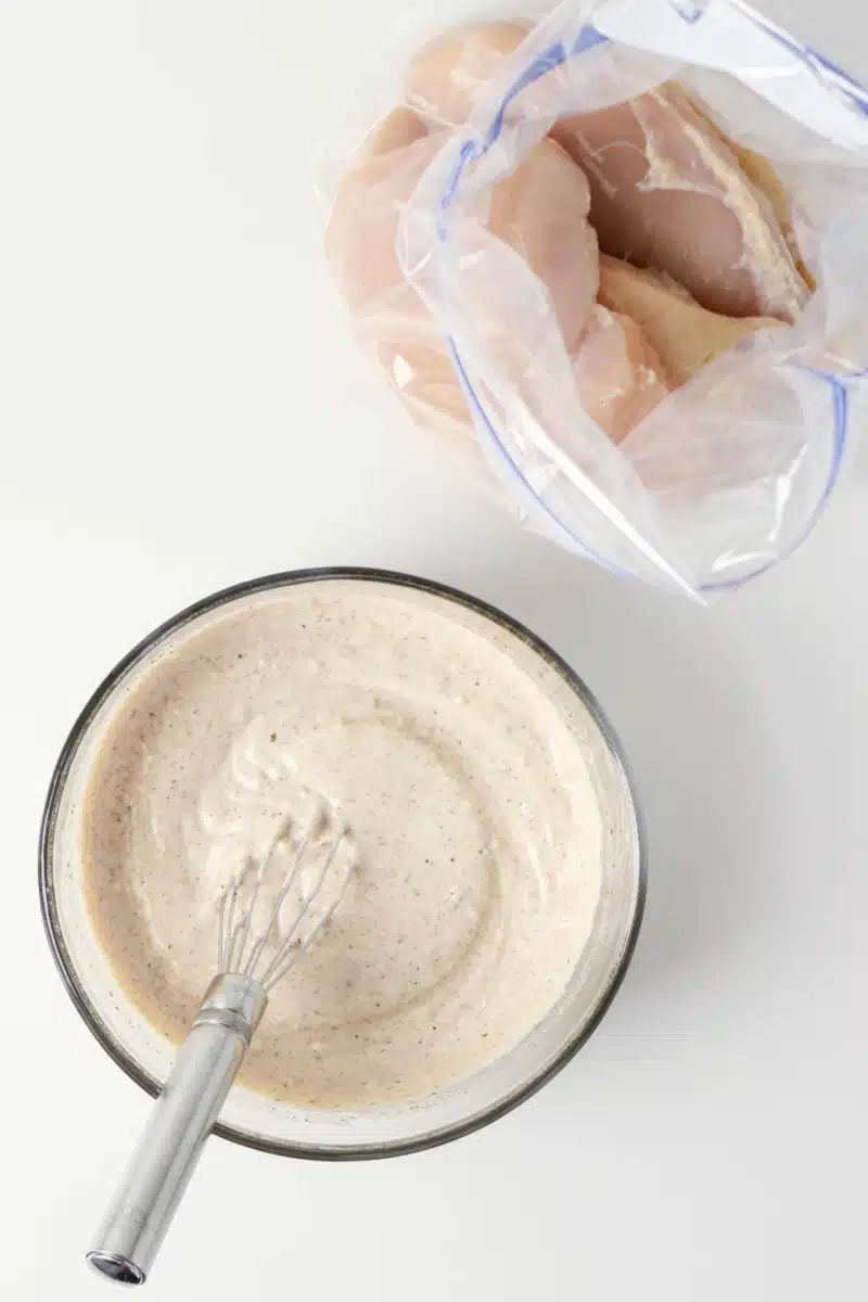 blending the marinade in a bowl and chicken in a food storage bag