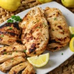 mainated Greek yogurt chicken breasts on a platter with lemon wedges