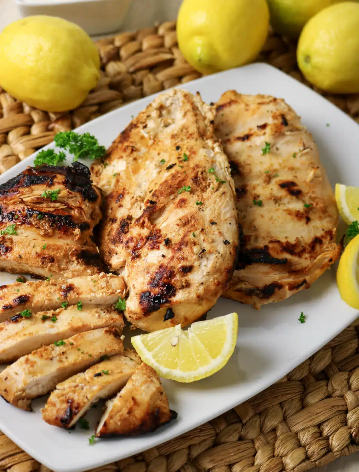 mainated Greek yogurt chicken breasts on a platter with lemon wedges
