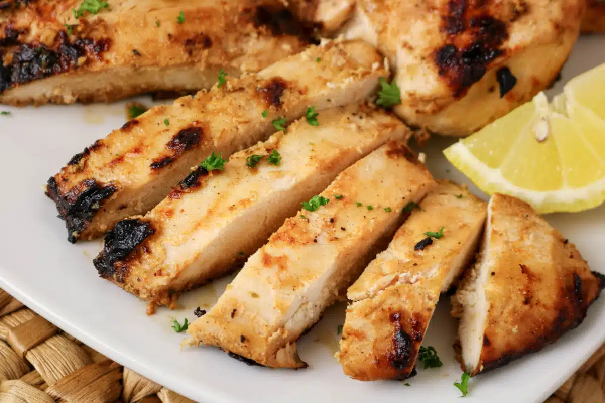 sliced chicken on a platter with lemon wedge