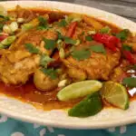 chicken curry with potatoes and peppers on an oval white platter