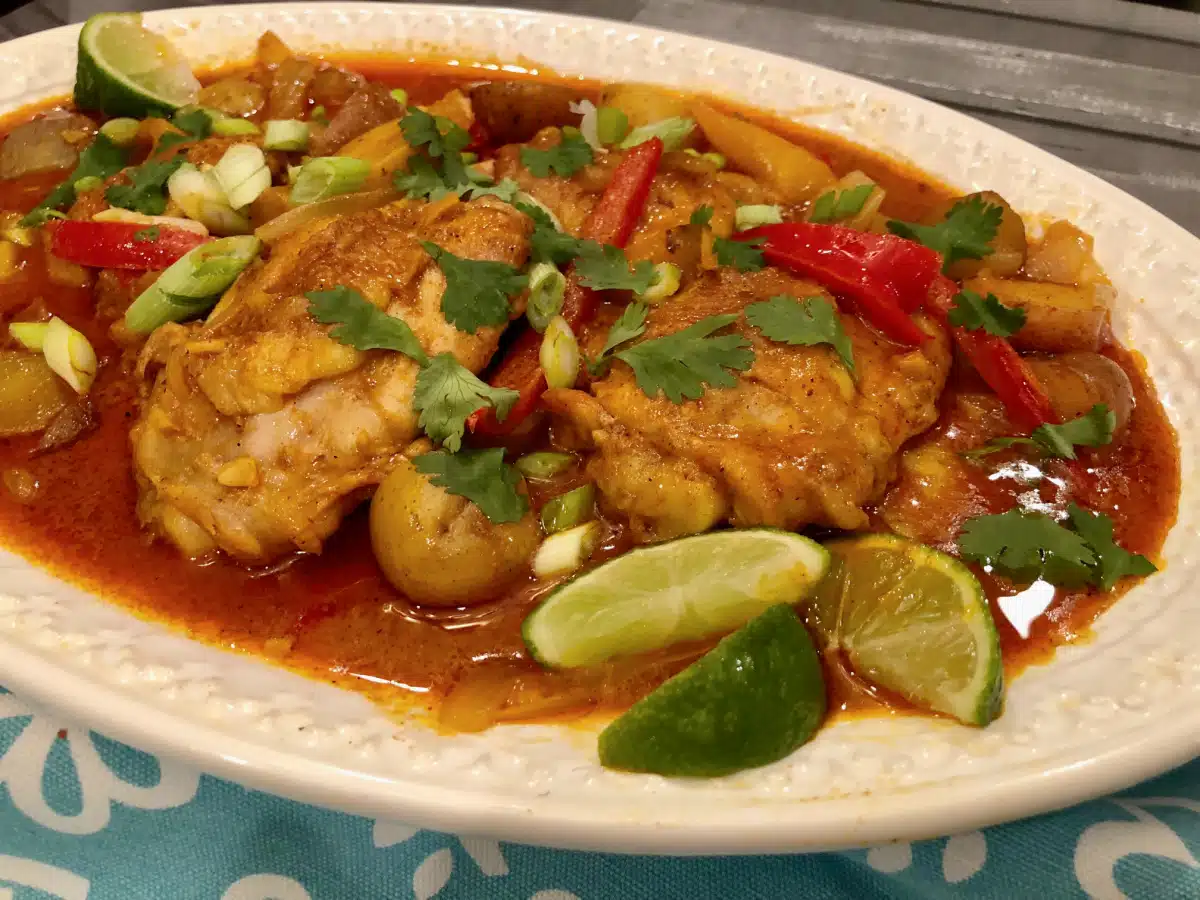 chicken curry with potatoes and peppers on an oval white platter